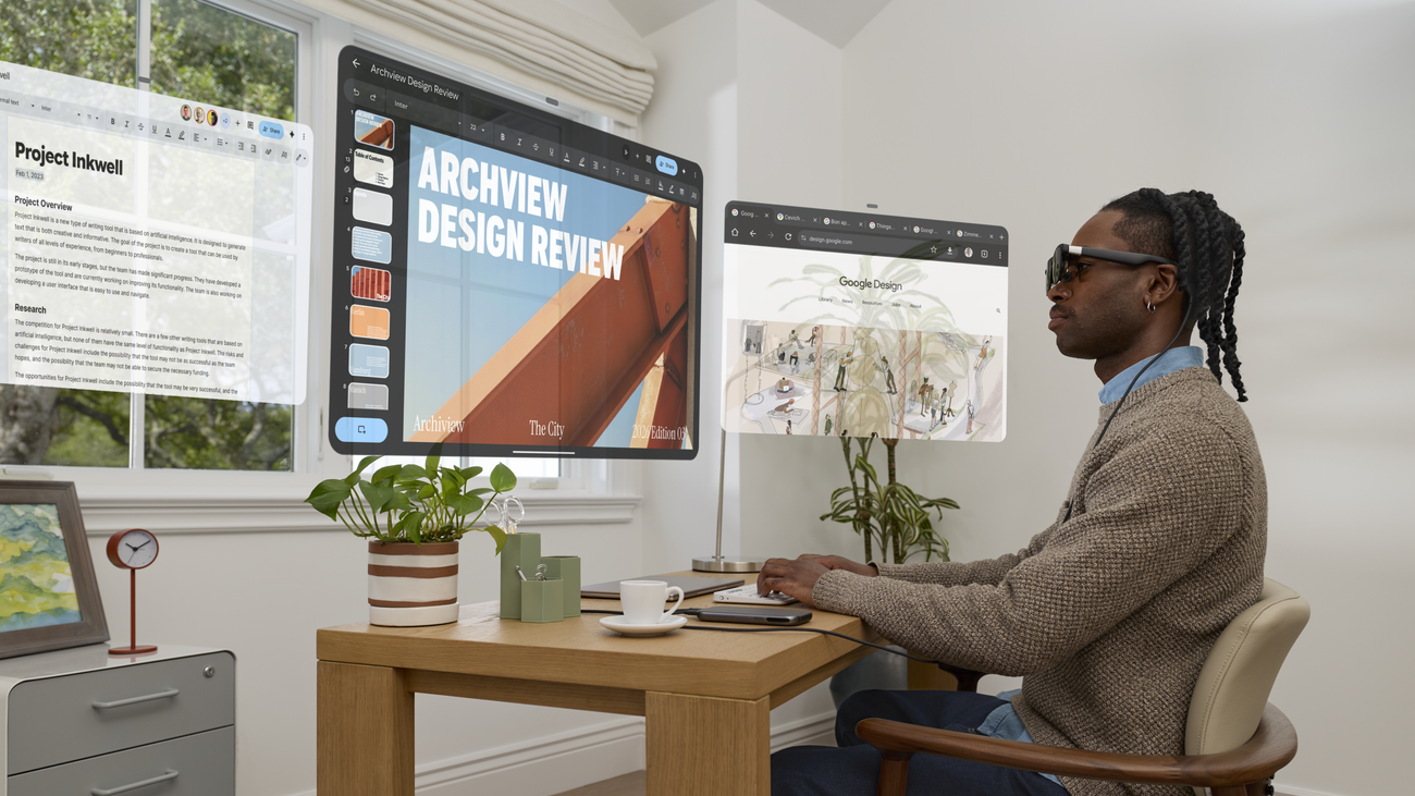 Person using XREAL AURA glasses with Android XR virtual screens in an office